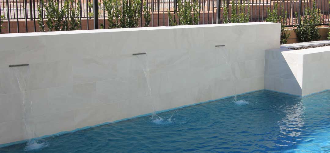 large format white stone pool tile bond beam wall with cascades and white grout